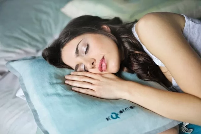 A girl is laying on a bed to get enough sleep for glowing skin 